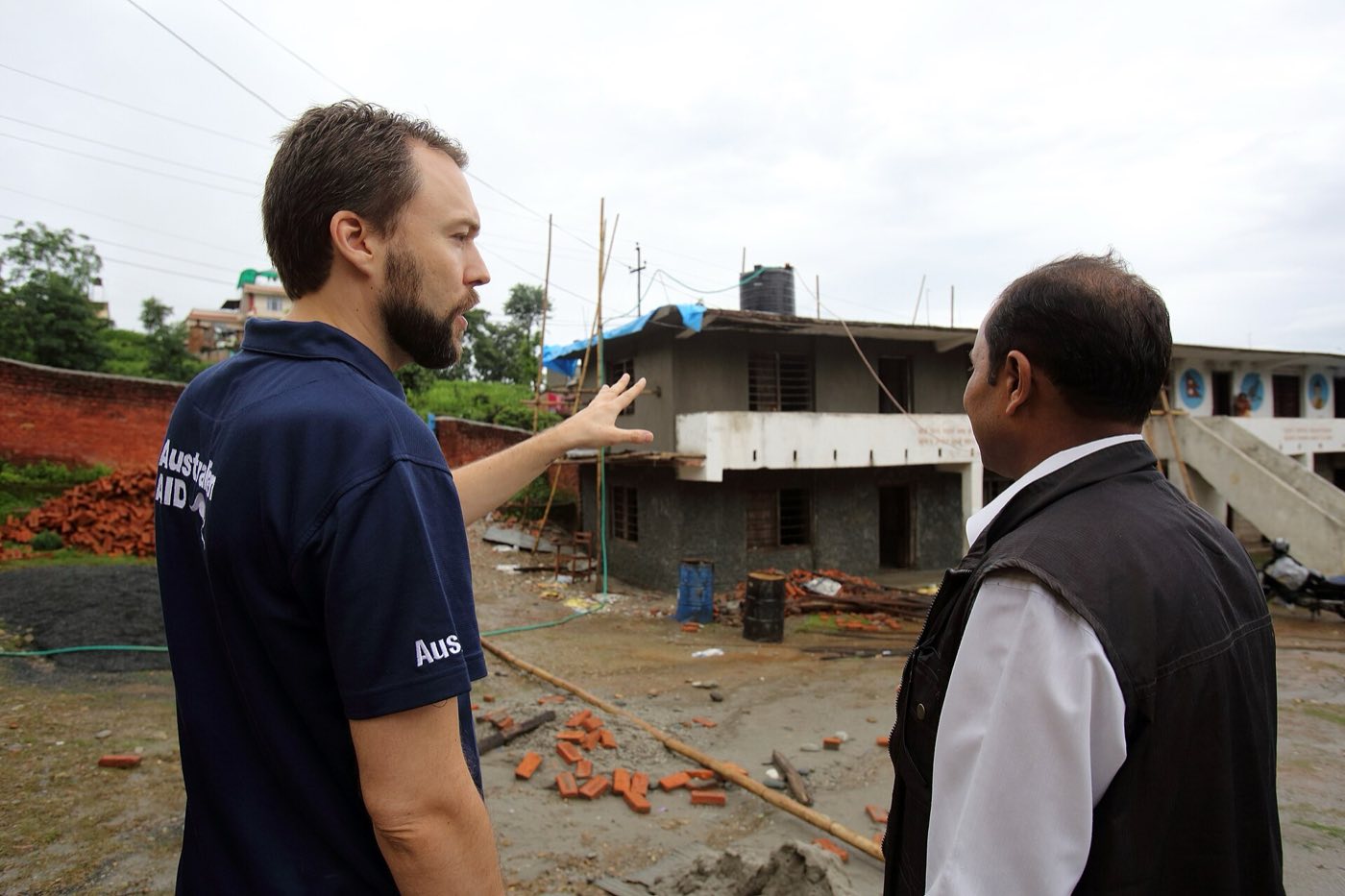 A district engineer shows visitors a school under construction. Photo: Department of Foreign Affairs and Trade, CC BY 4.0